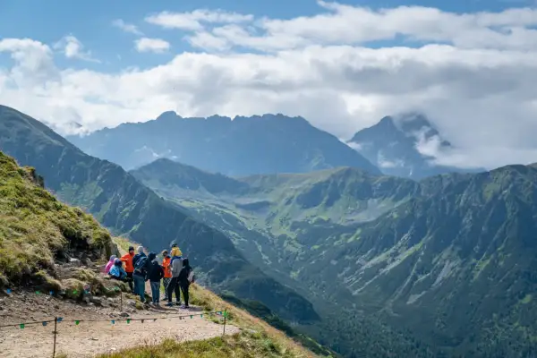 Grupa turystów na szlaku podziwia panoramę Tatr. Czy z Kasprowego widać Rysy? Tak, przy dobrej widoczności można dostrzec ich zarys.