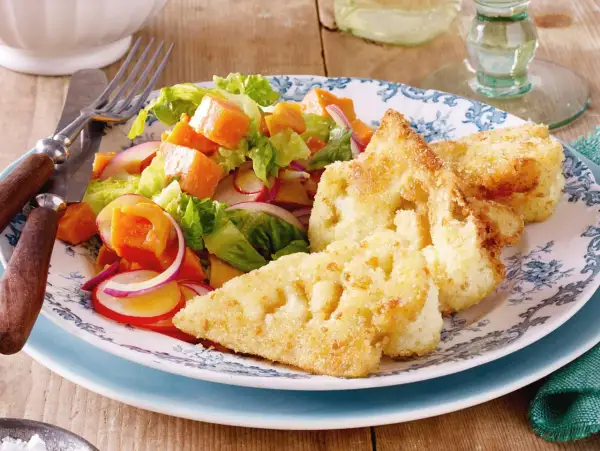 Knuspriges Blumenkohl Schnitzel mit einem bunten Salat aus Kürbis, Radieschen und roten Zwiebeln auf einem blumengemusterten Teller.