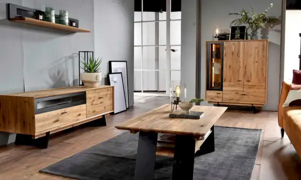 Przytulny salon w stylu boho loft. Drewniane meble, szara ściana i duża przeszklona drzwi tworzą ciepłą atmosferę.