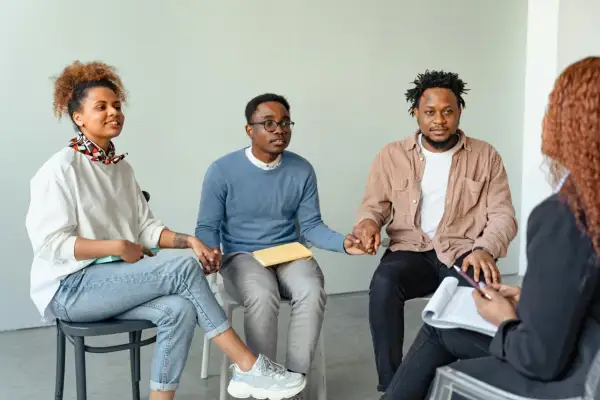 Grupo de personas en círculo, tomándose de las manos, fortaleciendo sus relaciones de amistad y apoyo mutuo.