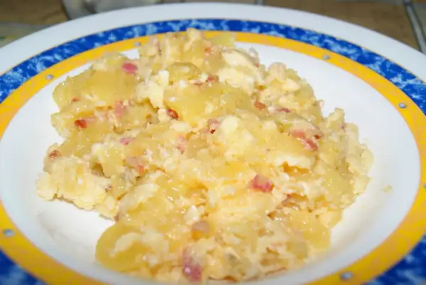 Patatas revueltas con huevo y trocitos de bacon, un plato casero delicioso y reconfortante.