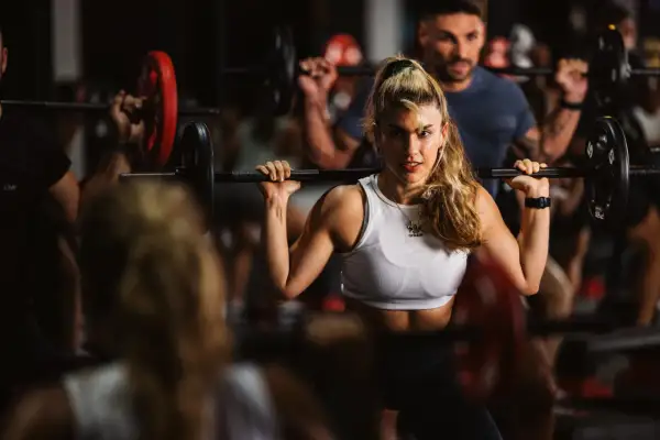 Frau beim intensiven **Freihantel training** im Fitnessstudio, fokussiert und stark.
