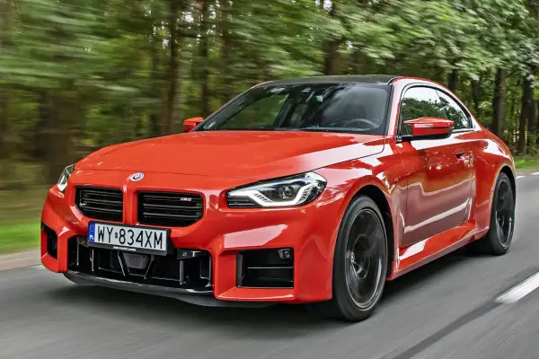 Pomarańczowe BMW M2 pędzi leśną drogą. Sprawdź aktualną bmw m2 cena i poczuj moc!