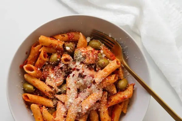 Penne z sosem pomidorowym, oliwkami i startą mozzarellą, posypane płatkami chili.