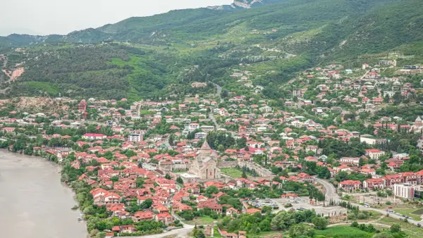 Malownicze miasteczko w Gruzji, z rzeką i zielonymi wzgórzami. Idealne miejsce na podróż, które warto uwzględnić w swoim gruzja przewodnik.