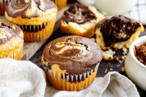 Marmorierte Muffins, perfekt für ein schnelles Muffins Rezept. Ein Muffin ist angeschnitten und zeigt den saftigen Teig.