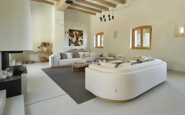 Salón moderno con sofás blancos, chimenea y suelo de microcemento sobre azulejos.