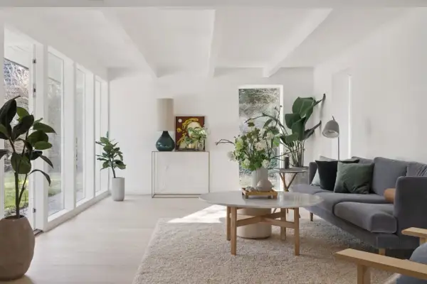 Ein helles, luftiges kleines Wohnzimmer skandinavisch einrichten mit grauem Sofa, Marmortisch und vielen Pflanzen.