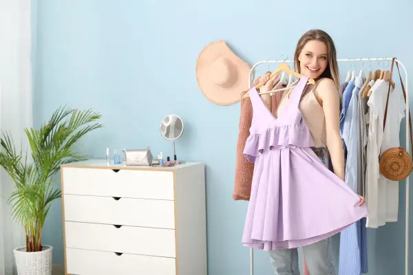 Ragazza sorridente prova un abito color glicine, pensando ai possibili abbinamenti vestiti per un look primaverile.