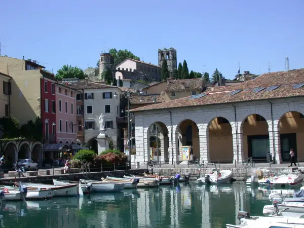 Porto di Desenzano: cosa vedere? Barche ormeggiate, case colorate e torri antiche sul lago.