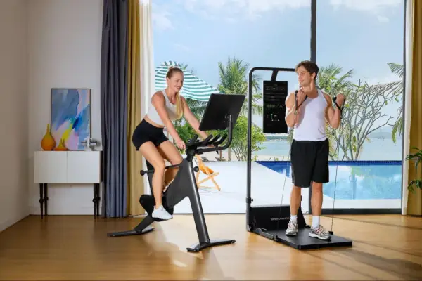 Ein Paar macht Ausdauertraining zuhause: Sie auf dem Fahrrad, er mit Widerstandsbändern. Der Blick geht auf ein tropisches Paradies.