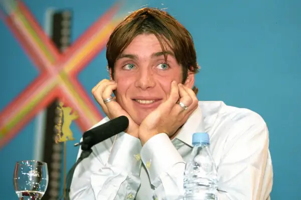 Cillian Murphy, znany z wielu filmów, z niebieskimi oczami i dłońmi opartymi o twarz, podczas konferencji prasowej.