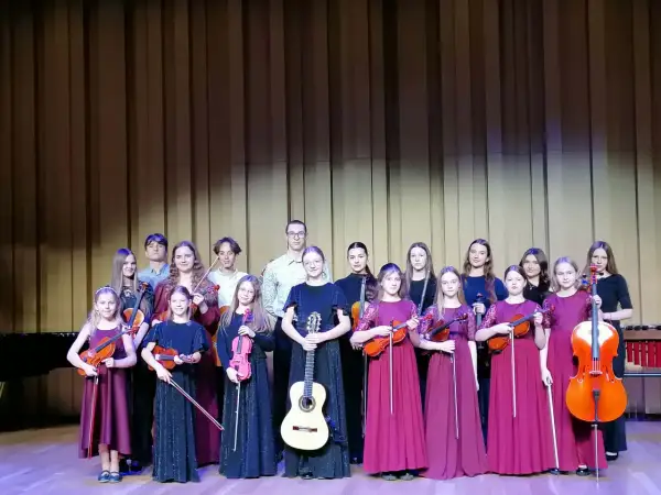 Młodzi muzycy, w tym Aleksandra Cieślik, gotowi do występu z instrumentami smyczkowymi i gitarą.