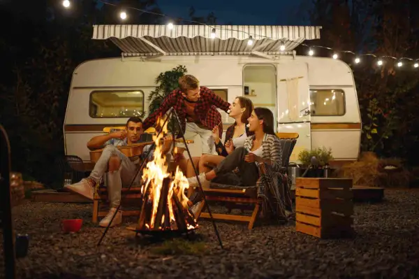 Amigos disfrutan de una fogata y malvaviscos junto a su caravana, una noche perfecta para aprender como acampar.