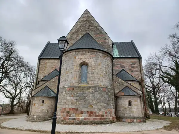 Kamienne mury kolegiaty w Kruszwicy, z charakterystycznymi absydami i kamienną latarnią, tworzą majestatyczny widok.