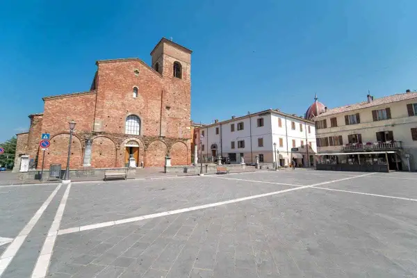 Piazza principale di Sarsina, dove si trova la Basilica di San Vincenzo Martire, con edifici storici e cielo azzurro.