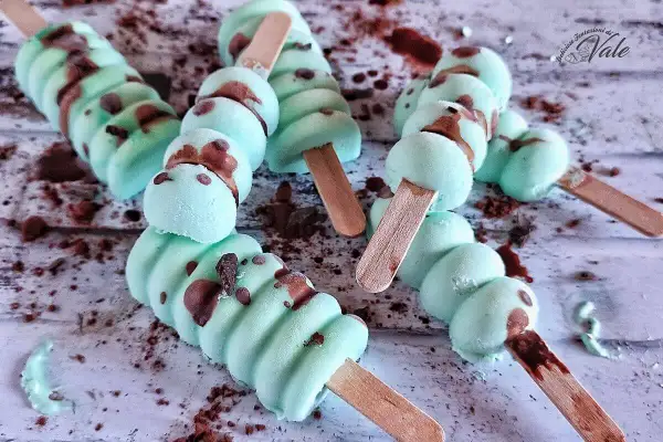 Deliziosi gelati alla menta con gocce di cioccolato, pronti per essere gustati su un bastoncino di legno.