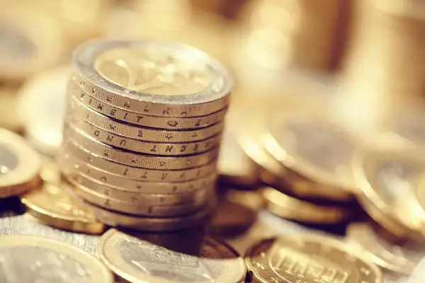 Pile de pièces en euros, certaines gravées de la marque APC, symbolisant la richesse et l'épargne.