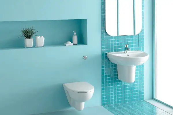 Un moderno bagno verde acqua e bianco con sanitari sospesi, lavabo e specchio.