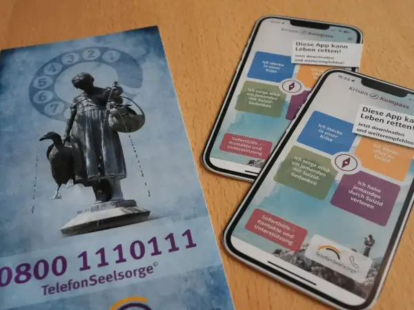Flyer und Smartphones mit der App "Krisen Kompass" zeigen Wege zur rettung aus der not. Die Telefonseelsorge bietet Hilfe.