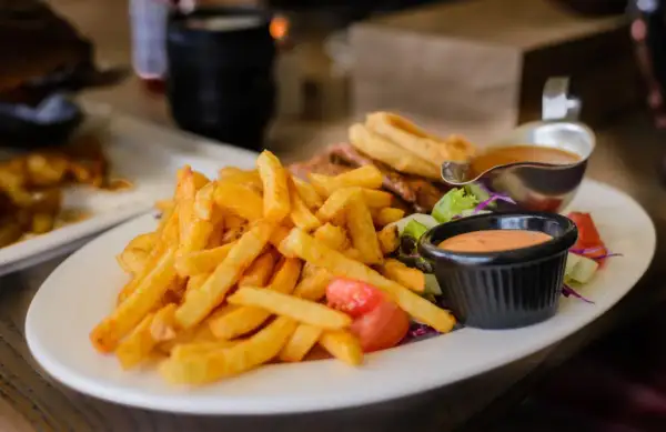 Chrupiące frytki z piekarnika, idealne na lekki posiłek. Zastanawiasz się nad ich kcal? Podane z sosem i sałatką.