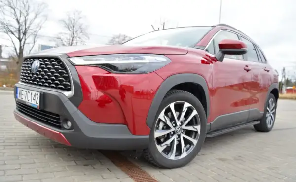 Czerwona Toyota Corolla Cross na zdjęciu prezentuje się imponująco, a jej wysoki prześwit sugeruje gotowość do pokonywania różnych dróg.