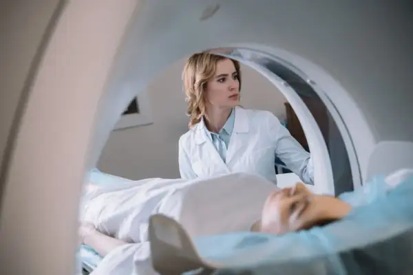 Lekarka nadzoruje badanie rezonans serca. Pacjent leży na stole aparatu MRI.