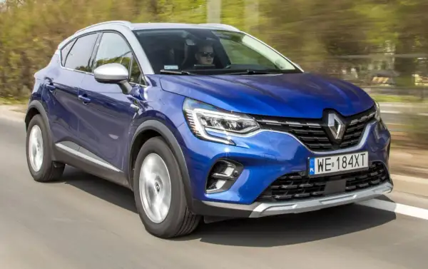 Błękitny Renault Captur 2019 pędzi po drodze, kierowca w okularach obserwuje trasę.