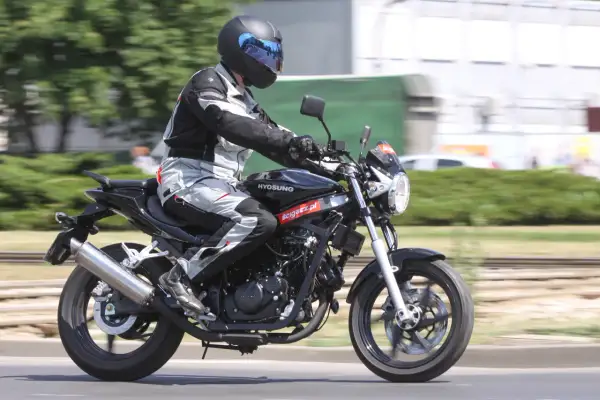 Motocyklista w pełnym stroju pędzi na czarnym Hyosung GT 125, ciesząc się jazdą.