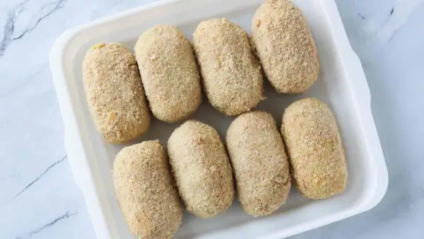Ocho croquetas empanadas listas para cocinar en la airfryer.