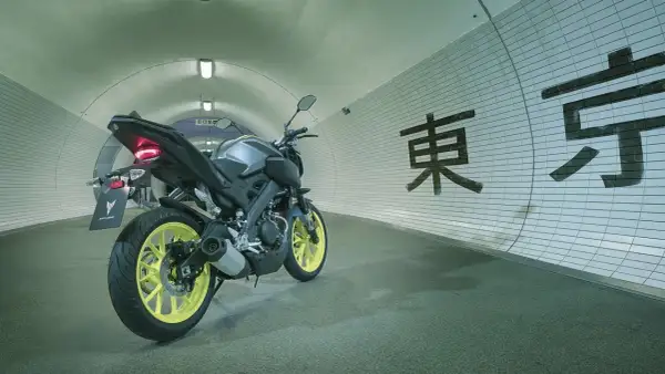 Yamaha MT-125 gris con llantas amarillas en un túnel con caracteres japoneses. ¡Lista para alcanzar su yamaha mt 125 velocidad maxima!