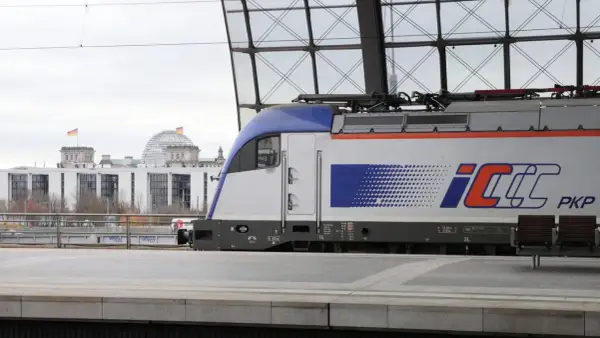 PKP Intercity Zug mit dem Logo "IC" und "PKP" steht am Bahnsteig. Im Hintergrund das Reichstagsgebäude in Berlin. Neue Zugverbindung Berlin - Krakau.