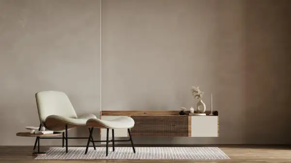 A minimalist living room with a textured limewash wall, a modern chair and ottoman, and a floating media console.