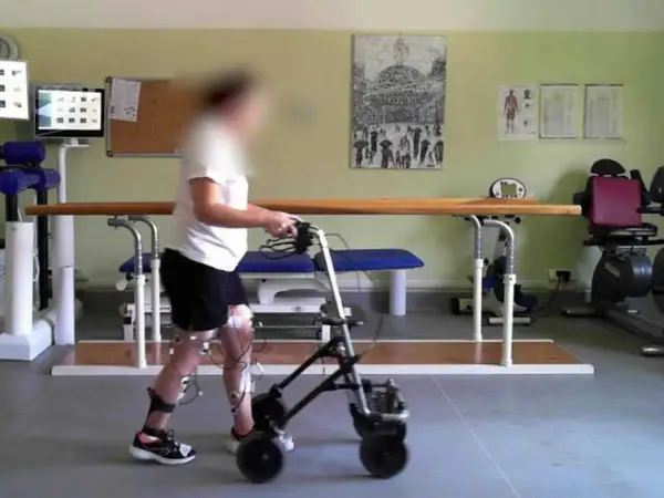 Persona con invalidità cammina con deambulatore, sensori alle gambe per neurostimolatore midollare.