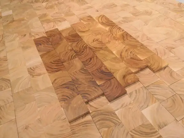 Patrón de suelo de madera cerezo con vetas circulares, algunas piezas más oscuras que otras, creando un efecto de degradado.