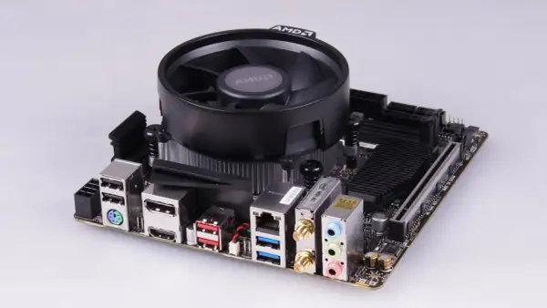 Mainboard mit AMD-Kühler, bereit für einen Ryzen 5 2400G Prozessor. Anschlüsse für USB, HDMI, LAN und Audio sind sichtbar.