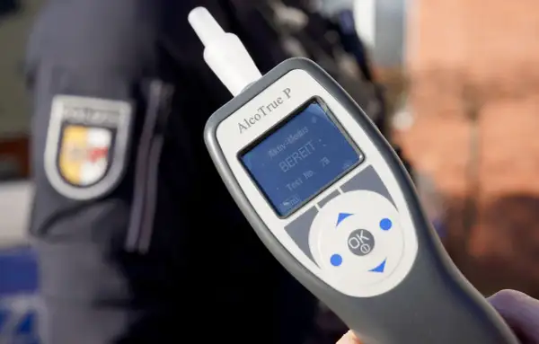 Polizist hält Alkoholtester. Das Gerät zeigt "BEREIT" an. Eine promille alkohol tabelle hilft, die Werte zu verstehen.