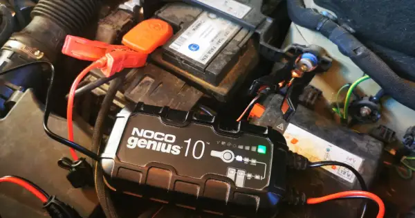 Ładowarka NOCO Genius 10 podłączona do akumulatora samochodowego, rozpoczyna proces odsiarczania akumulatora.