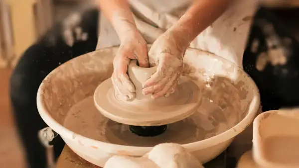 Mani esperte modellano l'argilla su un tornio, creando un pezzo unico di artigianato locale.