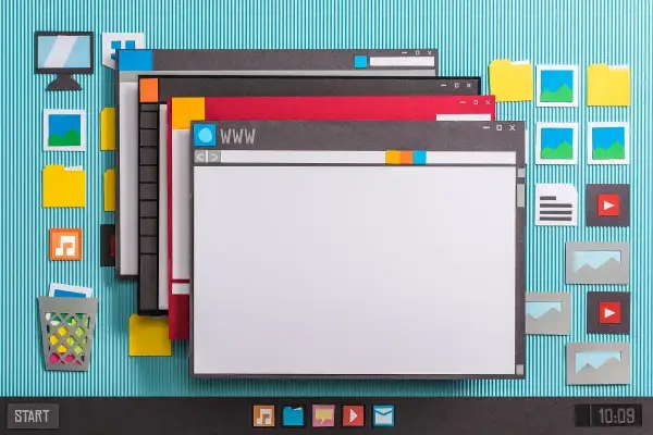 Papierowa symulacja pulpitu Windows 10 z oknami, ikonami i paskiem zadań. Asystent aktualizacji Windows 10 może być potrzebny do uporządkowania tego cyfrowego bałaganu.