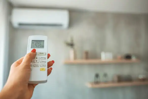 Main tenant ajuste la température de la climatisation pour un confort optimal, gérant la température clim été.