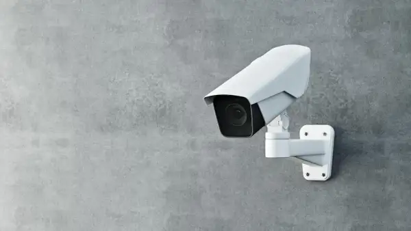 Une caméra de surveillance blanche est fixée sur un mur de béton. Cette caméra sans internet assure une sécurité discrète.
