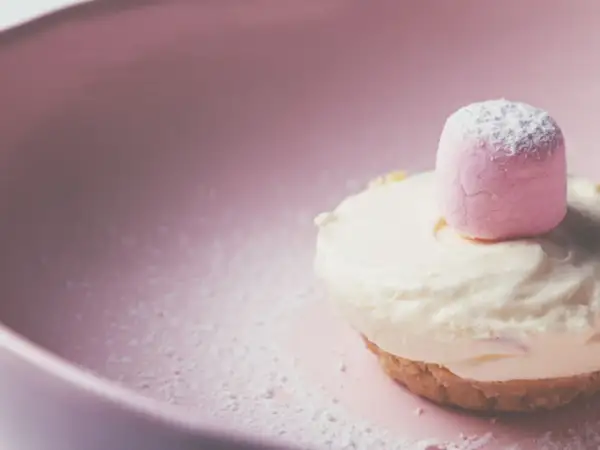 Delizioso namelaka al cioccolato bianco, con una soffice nuvola rosa in cima, adagiato su un piatto rosa cipria.