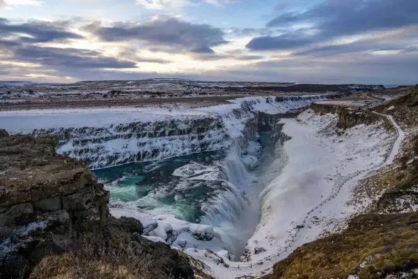 Potężny wodospad Gullfoss, część Złotego Kręgu Islandii, w zimowej scenerii. Woda spływa kaskadami do kanionu, otoczonego śniegiem i lodem.