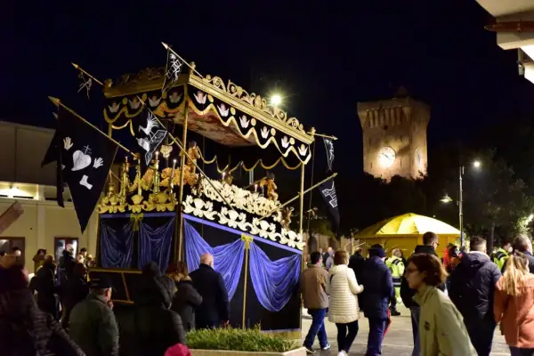 Serata a Porto Recanati con processione notturna e la torre dell'orologio illuminata.