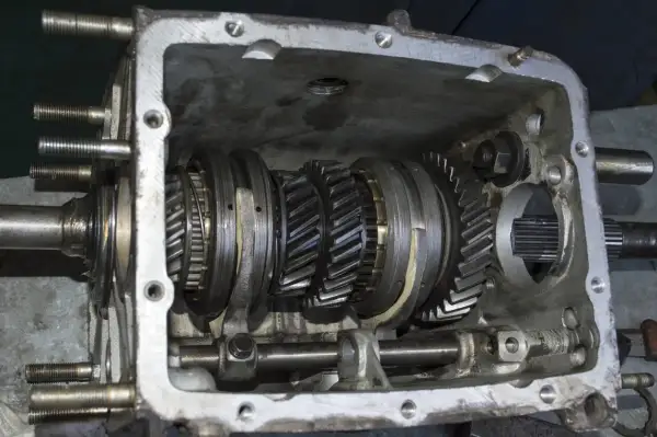 Vue détaillée d'une boîte de vitesses ouverte, montrant les engrenages et les synchroniseurs. Le mécanisme de synchro boite de vitesse est visible.