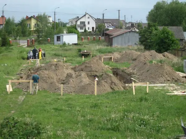 Prace ziemne pod budowę domu. Kopanie fundamentów, hałdy ziemi i pracownicy. Zastanawiasz się, ile kosztuje wykopanie fundamentów pod dom?