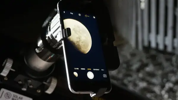 Telefon z aparatem uchwycił zdjęcie księżyca w pełni, widocznego przez teleskop.