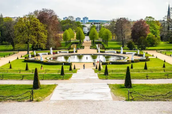 Ein prächtiger Park mit einem runden Teich, Statuen und gepflegten Rasenflächen. Ein ideales Motiv für Ausflugsziele Potsdam.