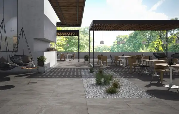 Spazio esterno moderno con tavoli, sedie e altalene, pavimentato con eleganti mattonelle per esterni grigie.